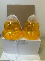 Two orange plastic wasp traps on top of white box