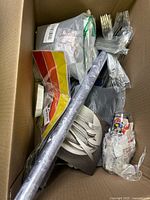 Top view of box showing assorted items including plates, rod, tape