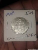 Reverse of 1964 Canadian 50 cent coin showing coat of arms in 2x2 holder