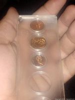 Front view of plastic holder showing three inserted coins and one empty slot