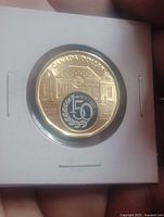 Reverse side of colourized 2023 Canada $1 coin showing building and 150 motif