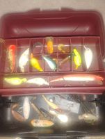Open tackle box showing top tray with multiple fishing lures