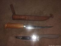 Wood-handle fillet knife, plastic-handle fillet knife, leather sheath laid out
