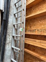 Full view of ladder rails and rungs leaning against wall