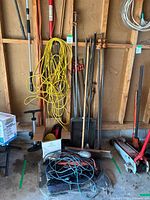 Wide view of assorted long-handle tools, extension cord, clamps, floor jack