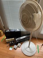 Lot overview showing fan, boombox, briefcase, timers, power bar and cords