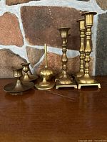 Six brass candle holders of varying designs grouped together