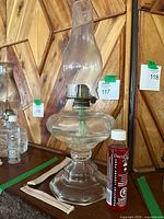 Full view of glass oil lamp with chimney on pedestal base, metal burner and visible wick