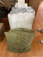 Front view of one sage/olive green pillow leaning against wrapped cushion.