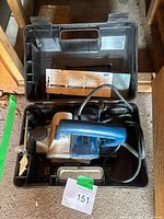 Planer in open plastic carry case with cord and manual sheet visible