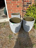 Three gray textured tapered planters grouped beside brick wall, showing size and appearance