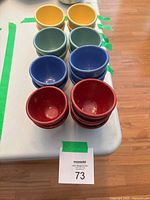 Stacks of red, blue, green and yellow ramekins with lot label visible