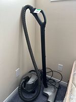 Vacuum canister, hose, wand, and powerhead standing against wall