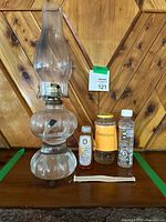 Full lot showing glass hurricane lamp, three fuel containers and spare wick
