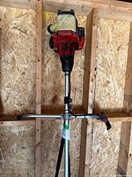 Full view of WeedBoss trimmer hanging showing engine, tank, handle
