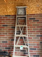 Full front view of ladder leaning against brick wall