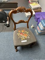 Full front view of carved wooden chair with needlepoint seat