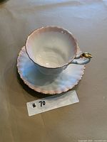 Side view of teacup on saucer showing pastel lustre and gold trim