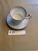 teacup displayed on saucer showing gradient glaze and gold trim