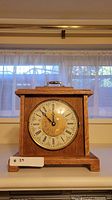 Front view of wooden mantel clock showing full case and dial
