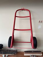 Front view of red hand truck showing frame and tires