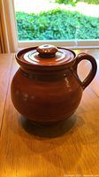 Front view of brown glazed clay pot with lid