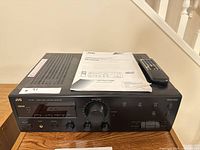 Front and top view of JVC receiver with manual and remote on top