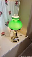 Full view of lamp showing green shade, brass base, clear chimney