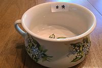 Side view of chamber pot showing handle and floral pattern