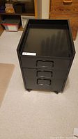Front view of black three-drawer cabinet on casters