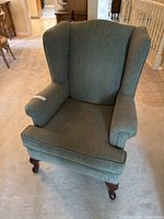 Front view of green wingback chair showing arms, cushion and legs
