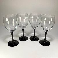 Full view of four clear goblets with black stems and bases