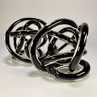 Pair of intertwined black glass knot sculptures side view