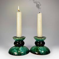 Two ceramic candle holders with candles for scale