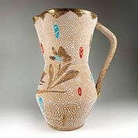 Full left profile of ceramic pitcher showing raised design and crackle glaze