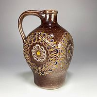 Front view of brown stoneware jug with floral medallion design