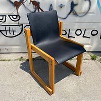 Front angle view of chair showing wooden frame and black vinyl seat
