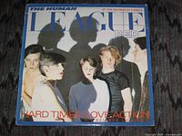 Front sleeve of The Human League 12" single Hard Times / Love Action
