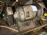 overall view of bench grinder showing housing, wire brush wheel, on-off switch