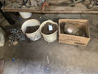 Overall lot showing two pails of chain, loose tire chains and boxed bench grinder