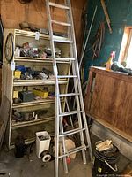 Full view of aluminum extension ladder leaning against shelving