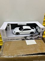 Front view of open Sharper Image box showing white Porsche Taycan Turbo S RC car and accessories