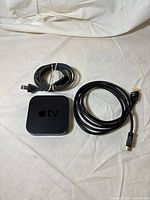 Apple TV with power cord and HDMI cable, top view