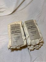 Front view of two bundled sets of cotton work gloves with paper labels