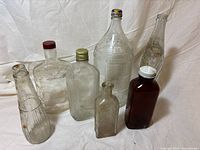 Seven assorted vintage glass bottles arranged for overview
