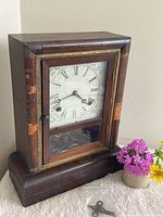 Full view of Gilbert wood mantel clock with key on table