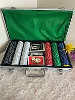 Open aluminum poker chip case showing chips, cards and dice