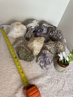 Group view of approximately ten mineral specimens beside tape for scale