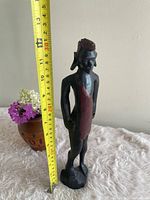 Full view of wooden tribal man figurine beside tape measure showing 12-inch height