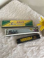 Both harmonicas and Hero case on fabric background
